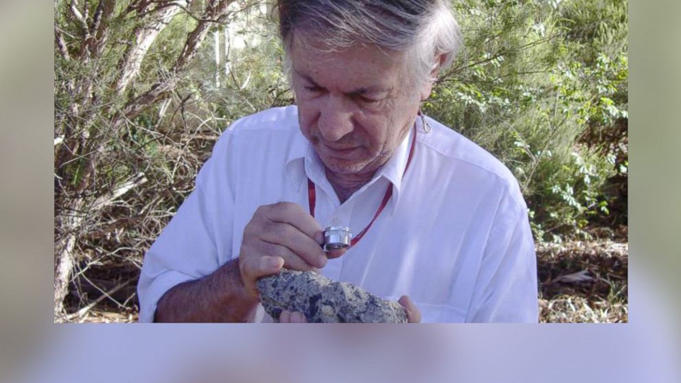 Australian National University's Dr. Andrew Glikson is pictured with a sample of suevite, a rock with partially melted material formed during an impact. 