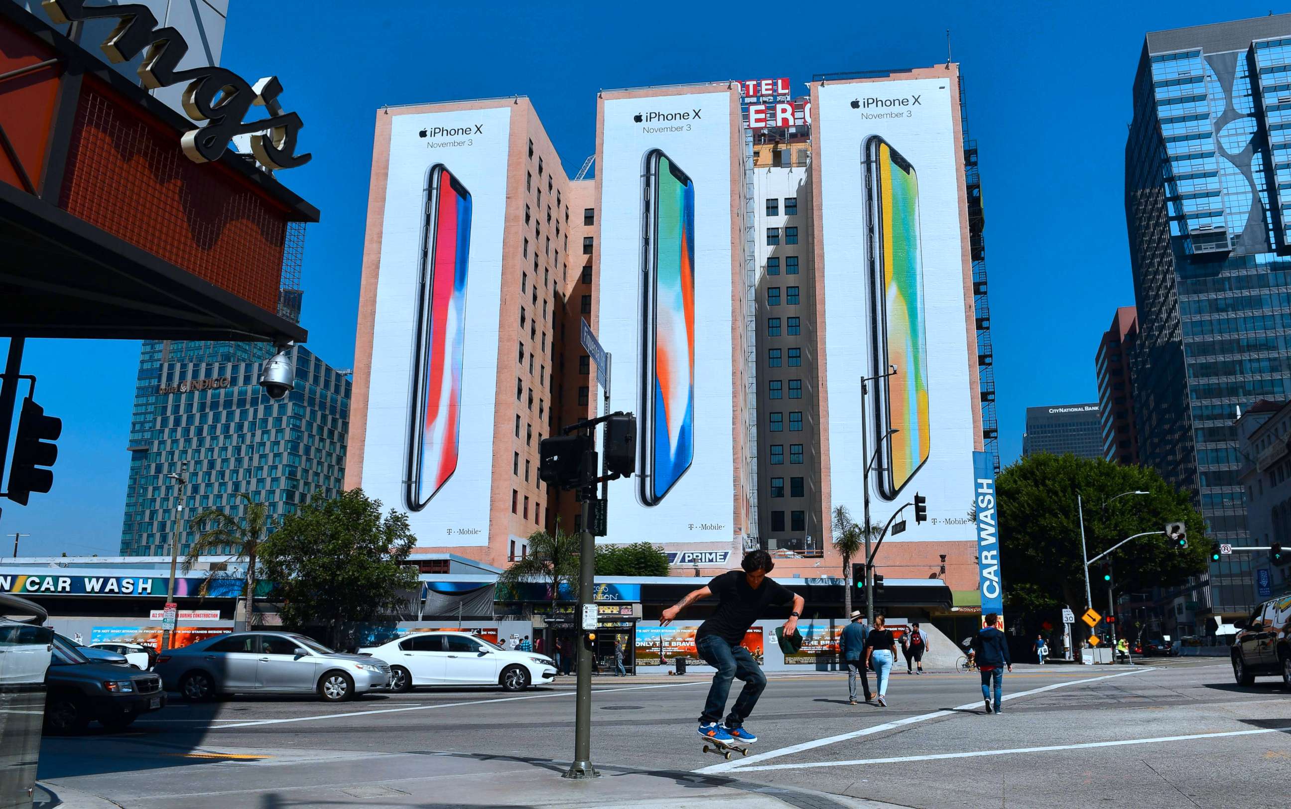 PHOTO: A skateboarder jumps the curb crossing a street in Los Angeles on Oct. 13, 2017, where advertising for Apple's new iPhone X, due for release on November 3, covers the sides of three buildings.