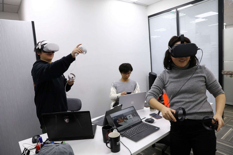 PHOTO: Pan Bohang, left, founder of vHome, a virtual reality (VR) social gaming platform, wearing Meta's Oculus VR headset speaks with a user during a virtual gathering, at an office in Beijing, Jan. 21, 2022.