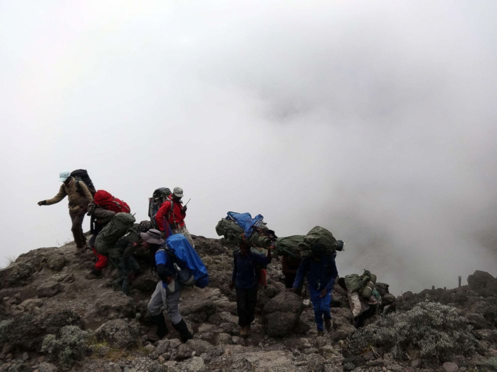 PHOTO: Porters carry equipment to the top of the Barranco Wall, at an elevation of 3700 meters, on Mount Kilimanjaro, Tanzania, in February 2019.