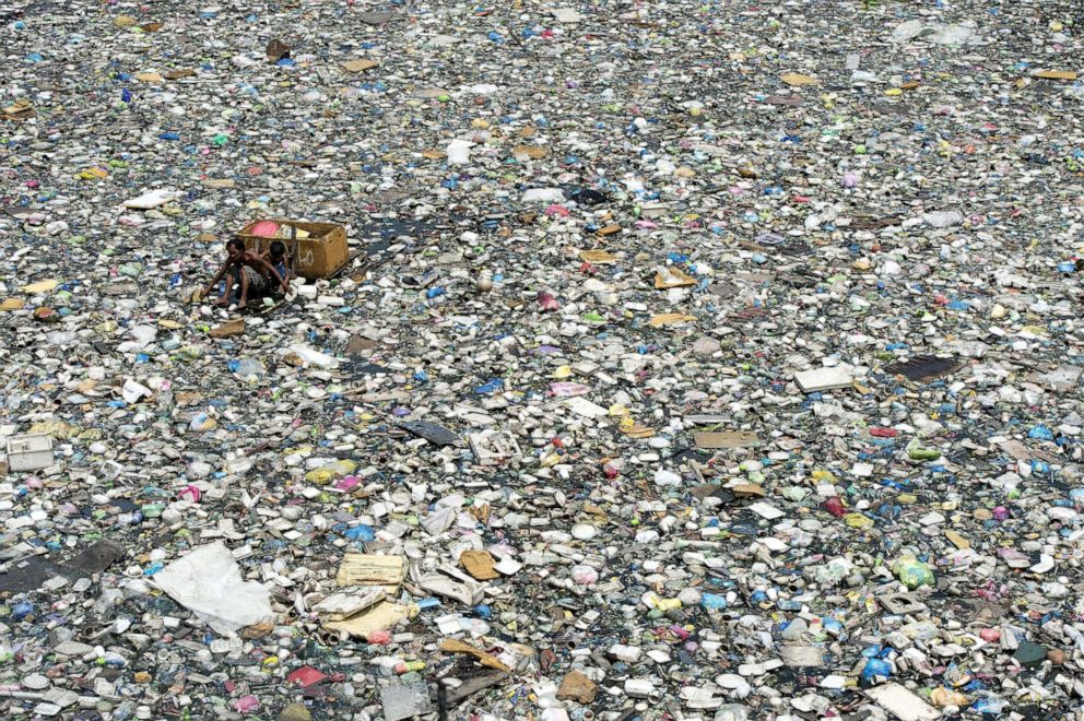 PHOTO: A father and son (left) on a makeshift boat made from styrofoam paddle through a garbage filled river as they collect plastic bottles that they can sell in junkshops in Manila on March 19, 2015.