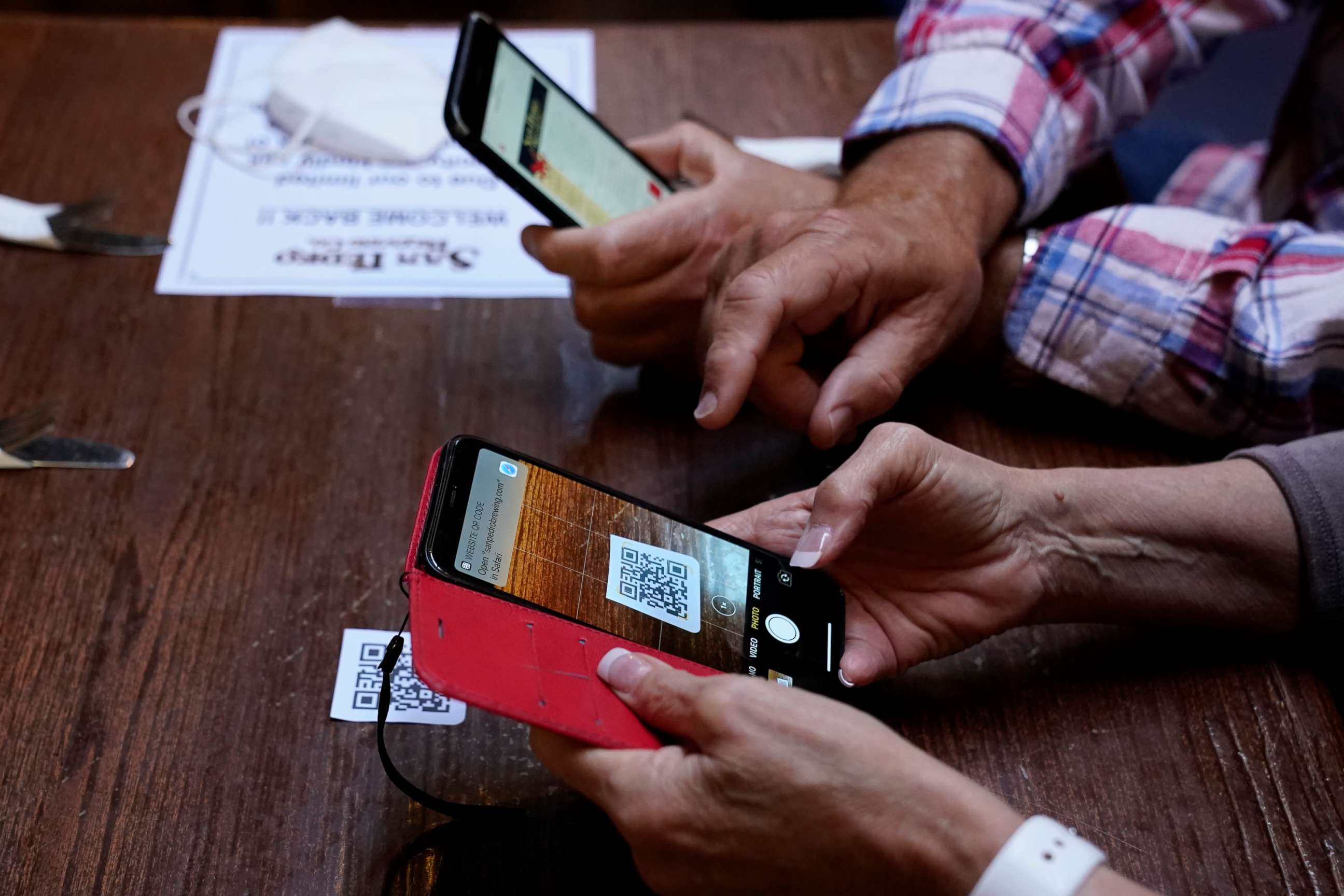 PHOTO: Customers use their phones to look up a digital menu via a QR code on the table in San Pedro Brewing Company, May 29, 2020, in Los Angeles.