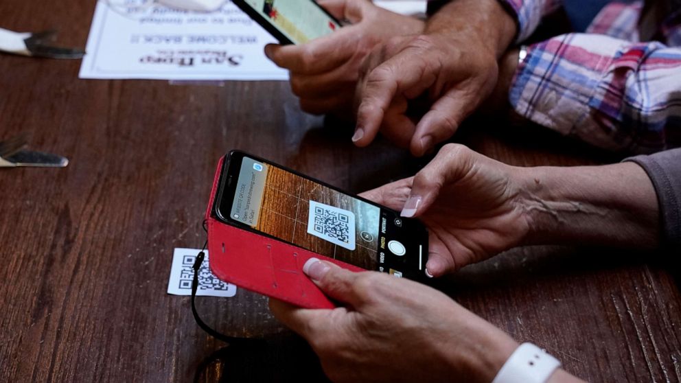 PHOTO: Customers use their phones to look up a digital menu via a QR code on the table in San Pedro Brewing Company, May 29, 2020, in Los Angeles.