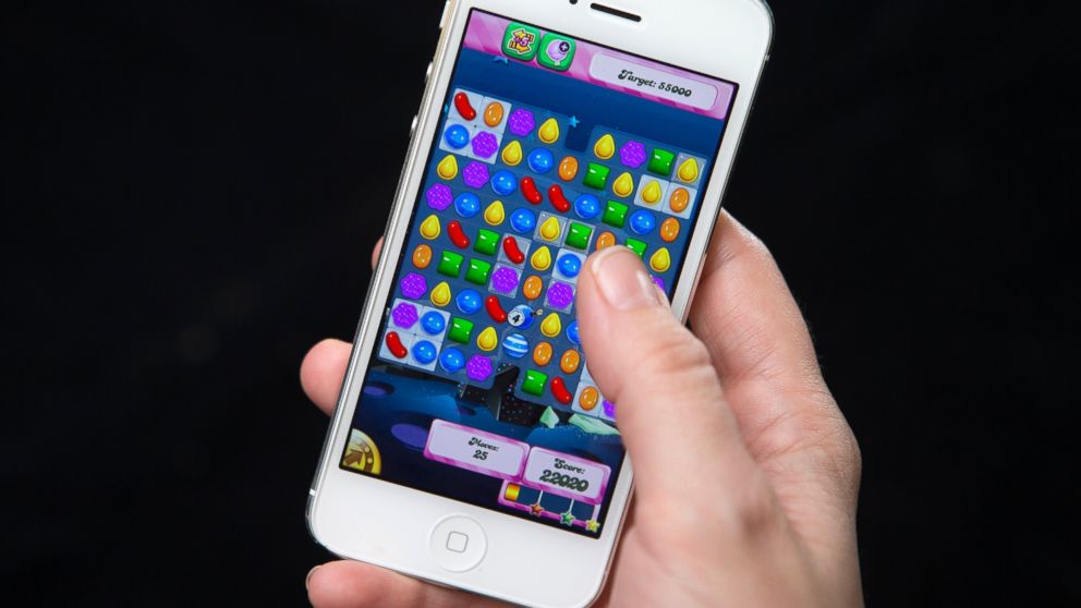 A woman poses for a photo illustration with an iPhone as she plays Candy Crush in New York, Feb. 18, 2014.