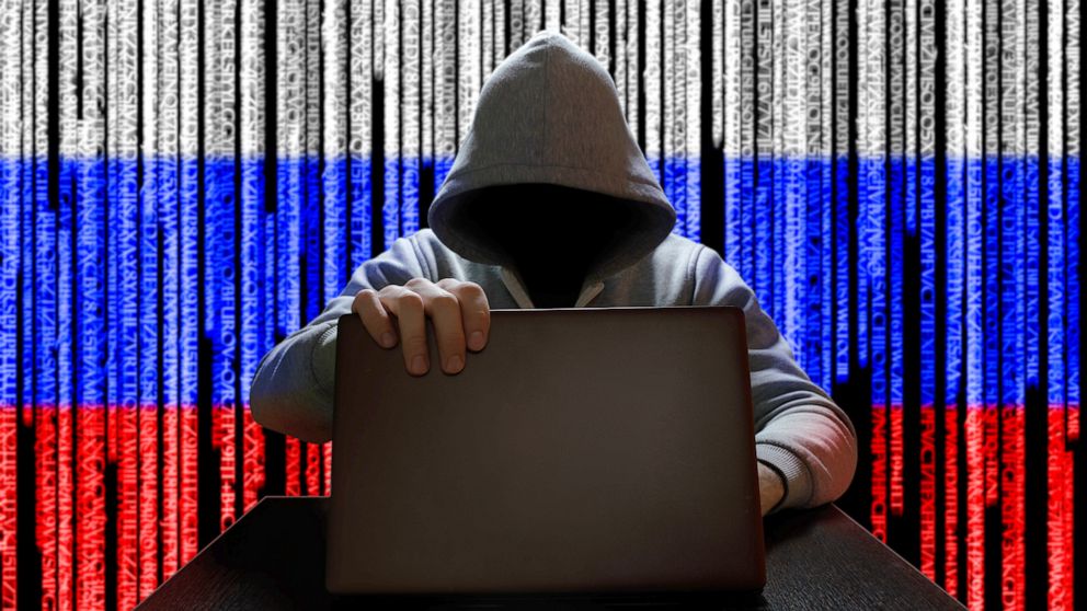 PHOTO: A hooded figure works on a laptop with a Russian Flag digital code backdrop in an undated stock image.