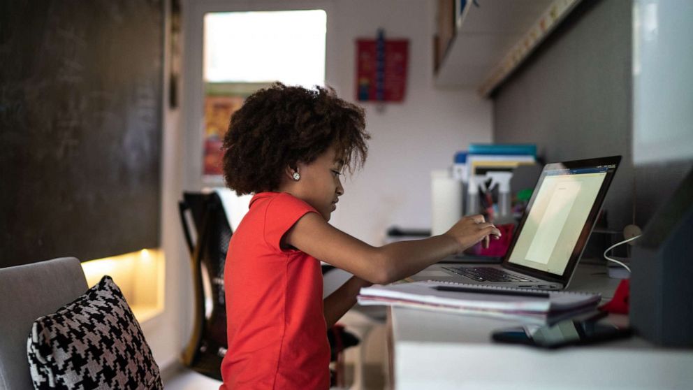 PHOTO: Young girl studying at home using a laptop.