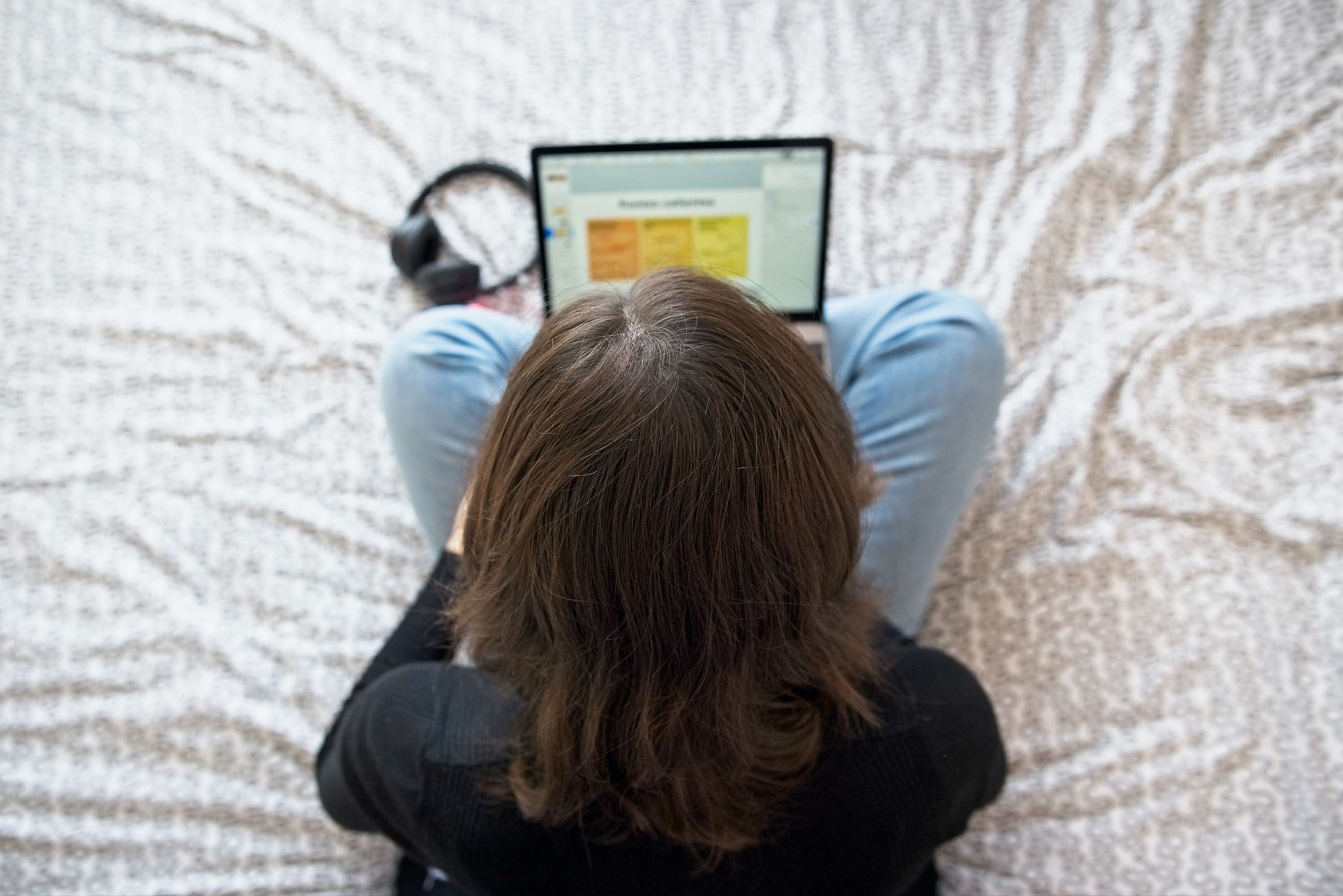 PHOTO: A teenage girl types on her laptop sitting on her bed