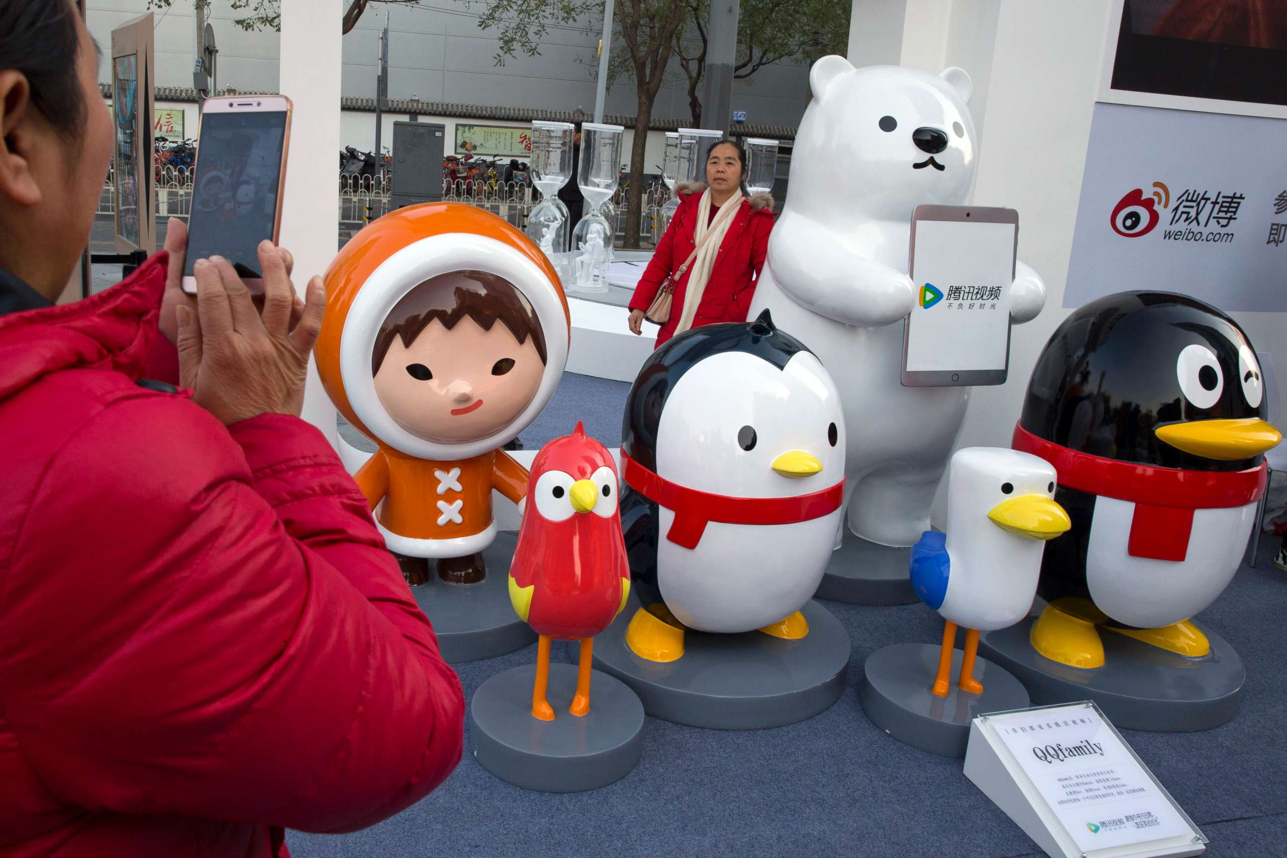 PHOTO: A woman takes photos near mascots for various social media platforms owned by Chinese internet conglomerate Tencent Holdings Limited during a promotion of Tencent Video, a video streaming service, in Beijing, Nov. 20, 2017.
