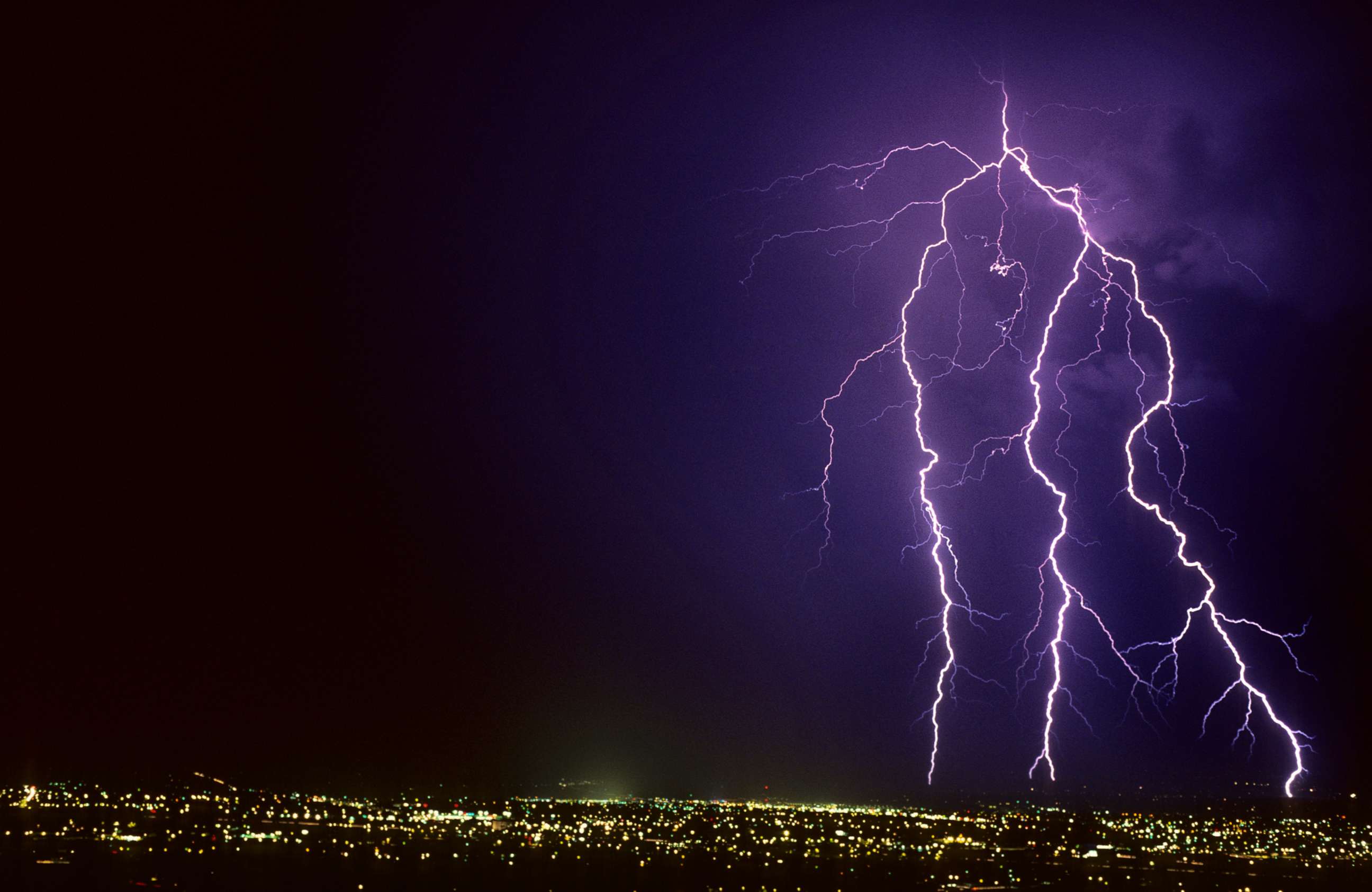 PHOTO: Forked cloud-to-ground lightning discharge with four strike points on the horizon, in Tucson, Ariz.