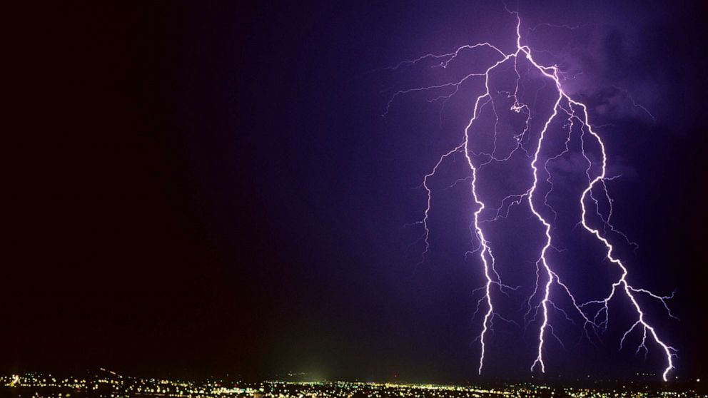 PHOTO: Forked cloud-to-ground lightning discharge with four strike points on the horizon, in Tucson, Ariz.