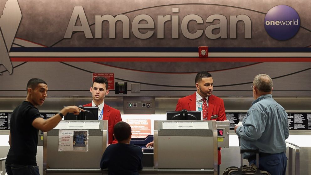 American Airlines employees help travelers at the ticket counter in the Miami International Airport on Feb. 12, 2013 in Miami. 