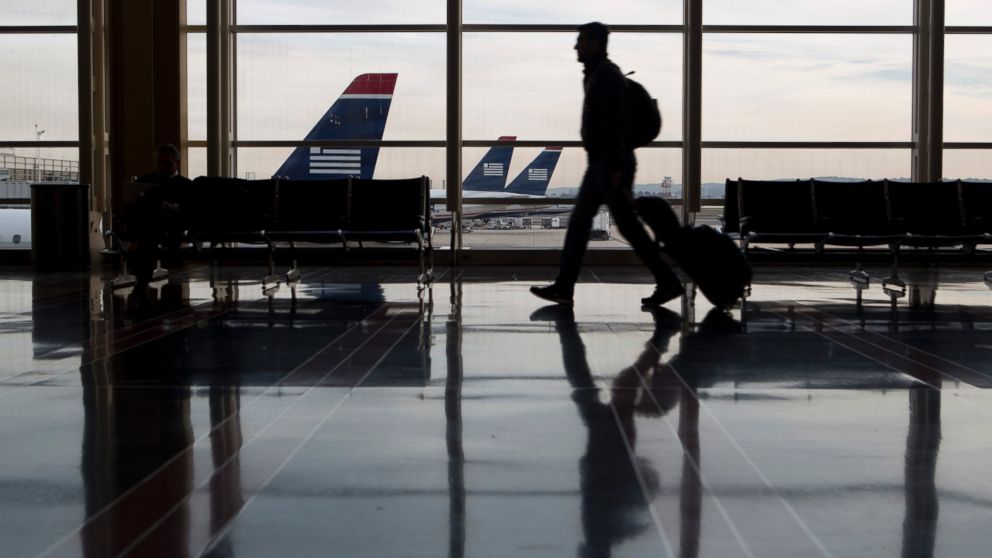 A traveler is seen walking past US Airways planes parked on the tarmac at Ronald Reagan National Airport in Washington, Nov. 15, 2013. 
