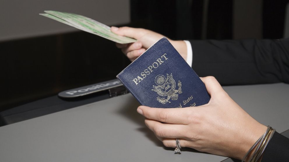 A woman is pictured showing a passport and airplane ticket in this stock photo. 