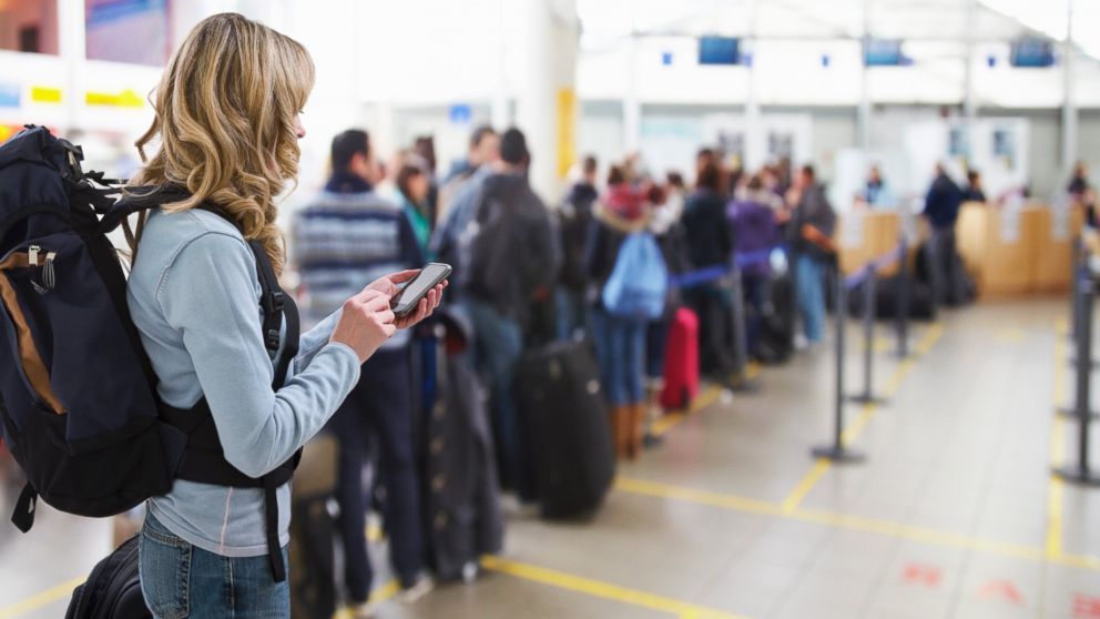PHOTO: A stock image of a female traveler texting at an airport check-in desk. 