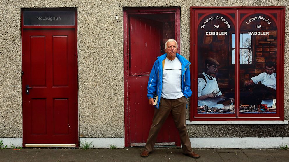 A man stands in front of an empty building, which has been covered with artwork to make it look more appealing, in the village of Bushmills on the Causeway Coast, Aug. 19, 2013.