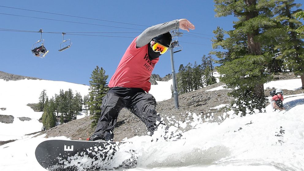 FILE - In this July 1, 2017 file photo, a snowboarder cuts throughout the snow at the Squaw Valley Ski Resort in Squaw Valley, Calif. A proposal to link a pair of Lake Tahoe ski resorts with a 2-mile-long gondola is moving closer to final approval. S