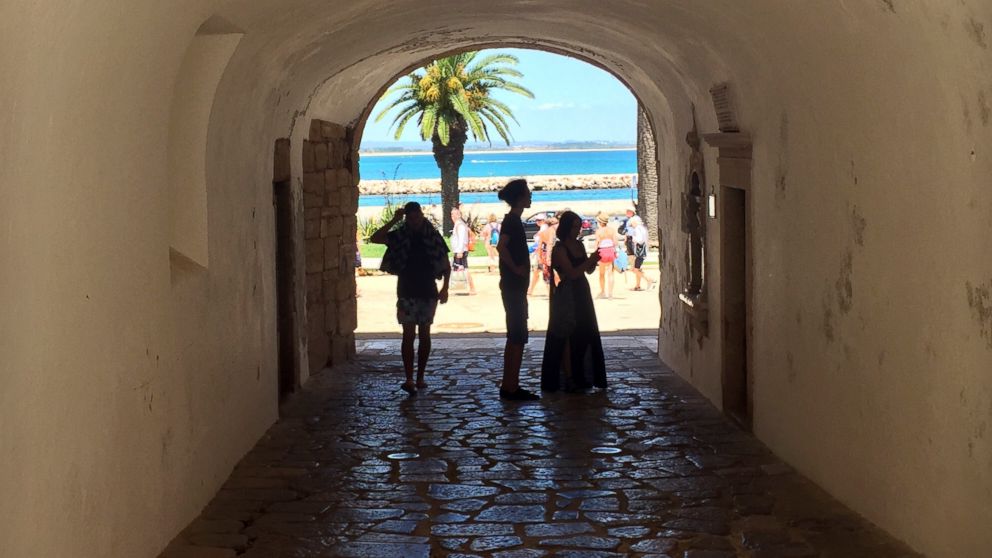 In this June, 27, 2018 photo, tourists walk through a tunnel at the medieval-area Castle of Lagos in Lagos, Portugal. Lagos, a striking Portuguese beach town of charming coastlines and slightly sandstone cliffs, is the birthplace of the African slave