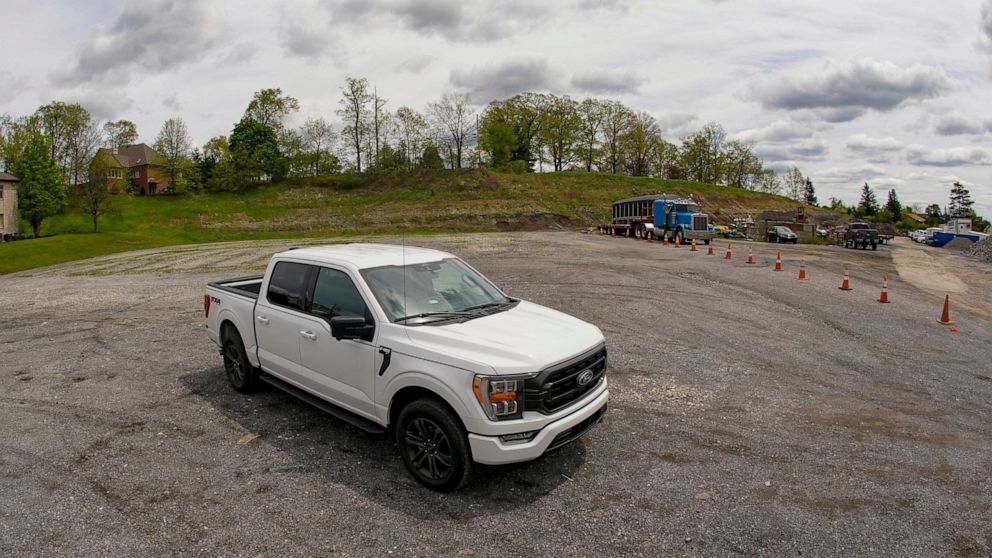 In this photo made on Thursday, May 6, 2021, a salesman from the Shults Ford dealership in Wexford, Pa. sits in one of the Ford F150 trucks at their nearby empty pickup truck inventory storage lot. Ford is warning that it expects to make only half th