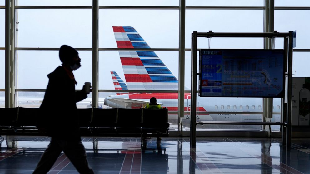 An American Airlines jet sits parked at a gate as light snow falls at Ronald Reagan Washington National Airport, Tuesday, Feb. 2, 2021, in Arlington, Va. American Airlines says bookings are coming back — they're nearly at pre-pandemic levels. As a re