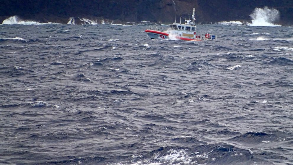 In this photo released by the U.S. Coast Guard, a coast guard vessel searches along the Na Pali Coast on the Hawaiian island of Kauai on Friday, Dec. 27, 2019, the day after a tour helicopter disappeared with seven people aboard. Authorities say wrec
