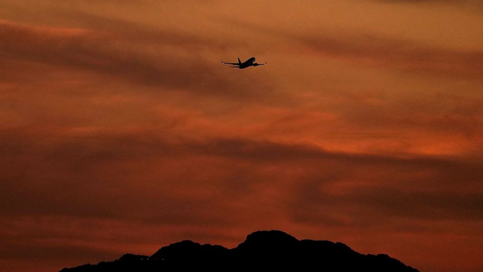 A passenger jet is silhouetted against the sky at dusk as it takes off from Sky Harbor Airport, Saturday, April 2, 2022, in Phoenix. Airlines have cancelled more than 3,300 U.S. flights this weekend and delayed thousands more, citing weather in Flori