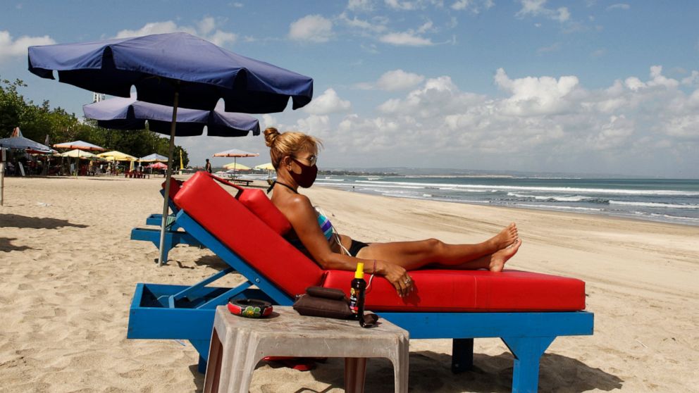 FILE - In this July 27, 2020, file photo, a tourist wearing face sunbathe as beaches are gradually reopening following months of lockdown due to the new coronavirus outbreak, in Bali, Indonesia. Indonesia said Monday, Oct. 4, 2021, that it plans to r
