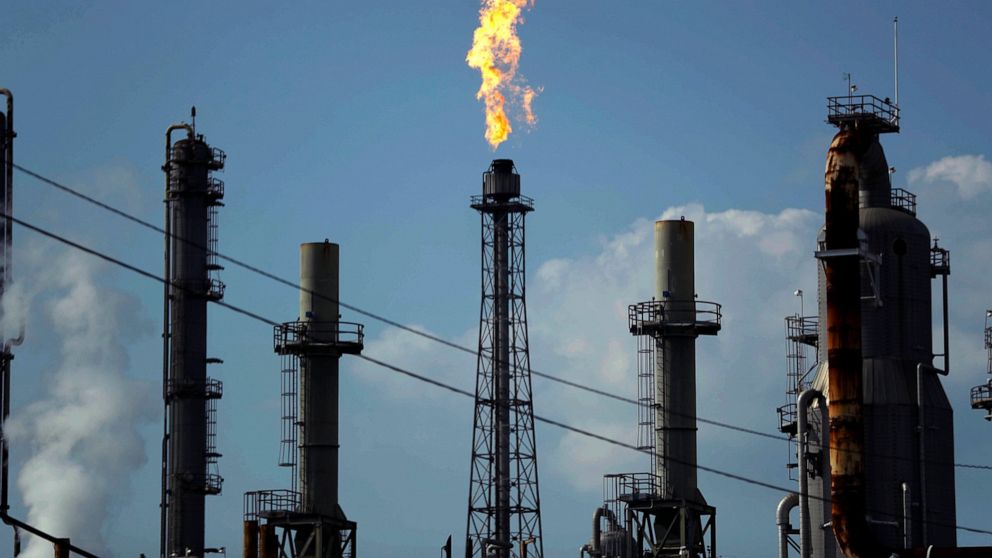 FILE - In this Thursday, Aug. 31, 2017, file photo, a flame burns at the Shell Deer Park oil refinery in Deer Park, Texas. With the viral outbreak spreading to more countries, the price of oil has dropped precipitously as global demand weakens even f
