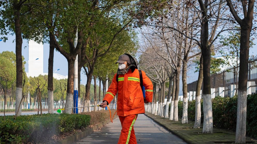 A worker wearing a face mask sprays disinfectant along a path in Wuhan in central China's Hubei Province, Tuesday, Jan. 28, 2020. China's death toll from a new viral disease that is causing global concern rose by 25 to at least 106 on Tuesday as the 
