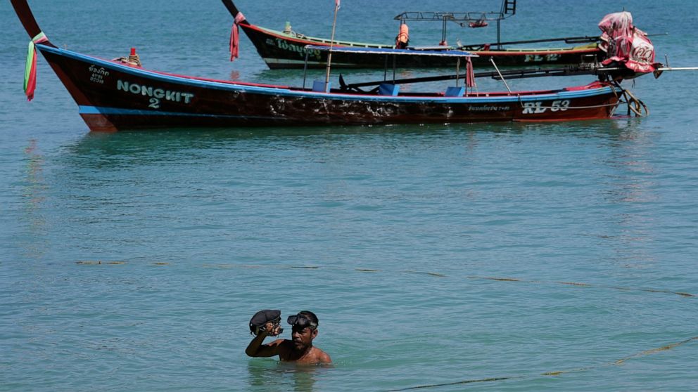 Tour boat owner Somsak Betlao wades in shore in the shallow waters of Patong Beach on Phuket province, southern Thailand, June 28, 2021. Somsak is putting his hope on a government scheme to bring the tourists back starting July 1 known as the "Phuket