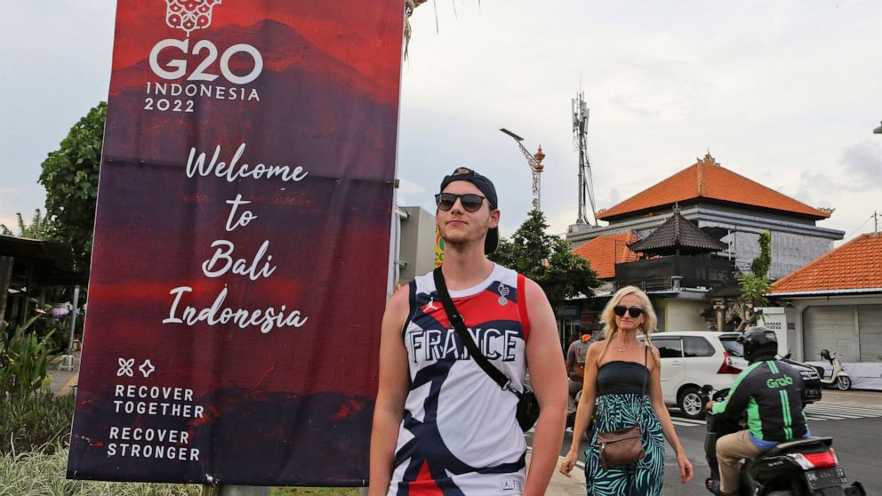 Tourists walk past a G20 banner in Nusa Dua, Bali, Indonesia on Friday, Nov. 11, 2022. The dozens of world leaders and other dignitaries traveling to Bali for the G-20 summit will be drawing a welcome spotlight on the revival of the tropical island's