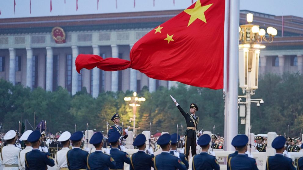 In this photo released by Xinhua News Agency, a member of the Chinese honor guard unfurls the Chinese national flag during a flag raising ceremony to mark the 73rd anniversary of the founding of the People's Republic of China held at the Tiananmen Sq