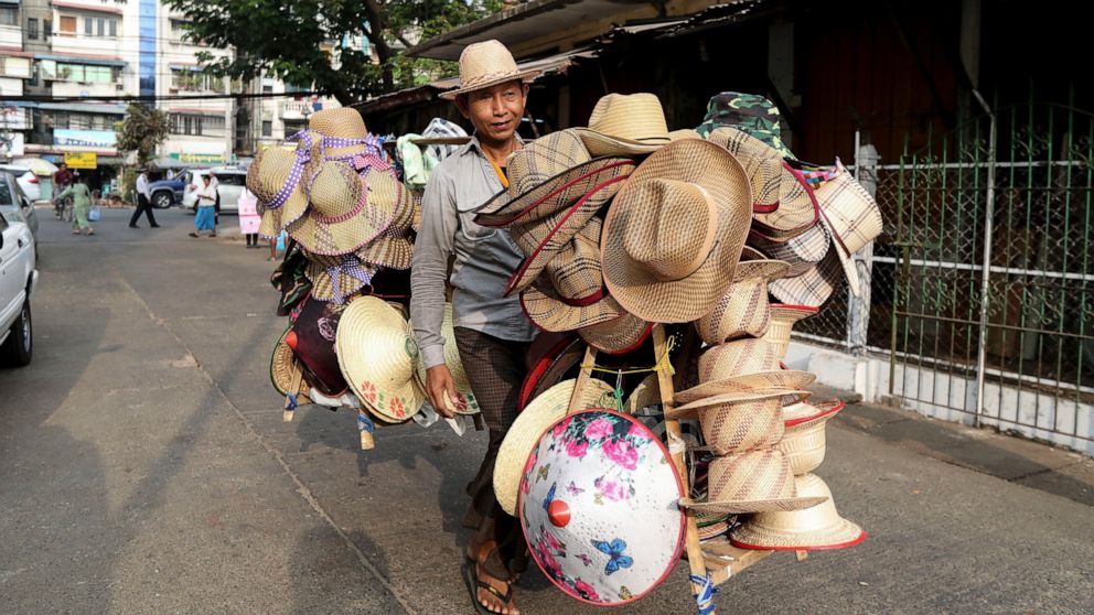 A vender carries bamboo hats for sale at a market in Yangon, Myanmar Saturday, March 21, 2020. About 1.6 million jobs were lost in Myanmar in 2021, the International Labor Organization, said in a report Friday, Jan. 28, 2022, with women suffering the