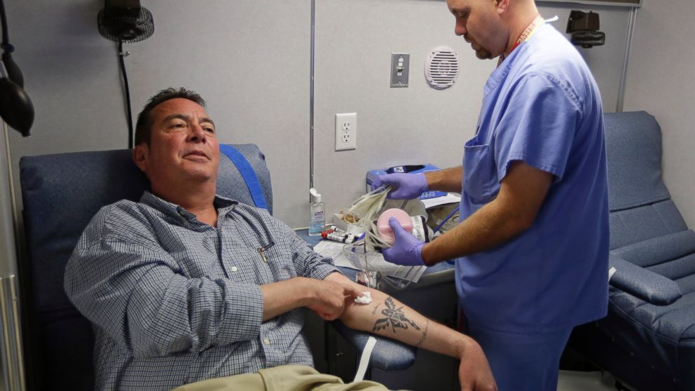 Technician Greg Snyder finishes up a blood draw from Chris Page after he donated blood in an Indiana Blood Center Bloodmobile in Indianapolis, Aug. 20, 2013.