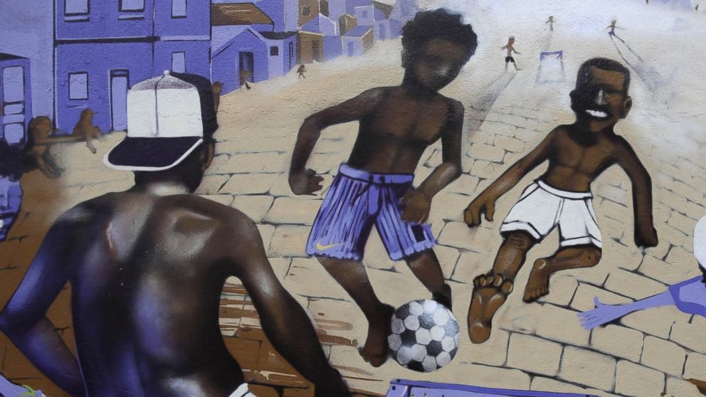 PHOTO: A wall decorated with a mural depicting children playing soccer at street in a favela stands in Rio de Janeiro, Brazil, May 27, 2014. 