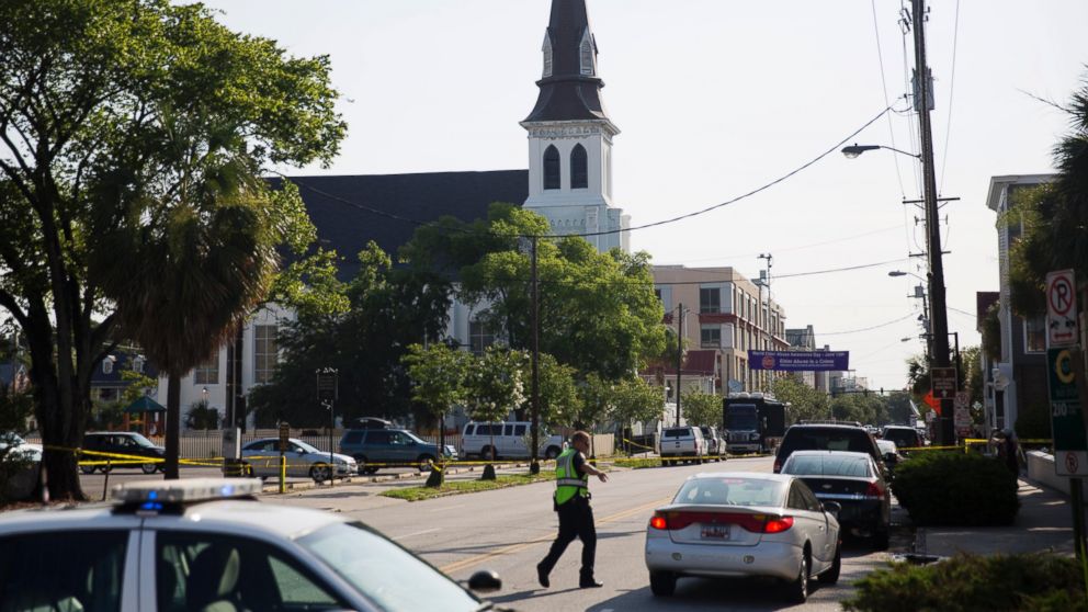 The steeple of Emanuel AME Church rises above the street as a police officer tells a car to move as the area is closed off following a shooting, June 18, 2015 in Charleston, S.C.