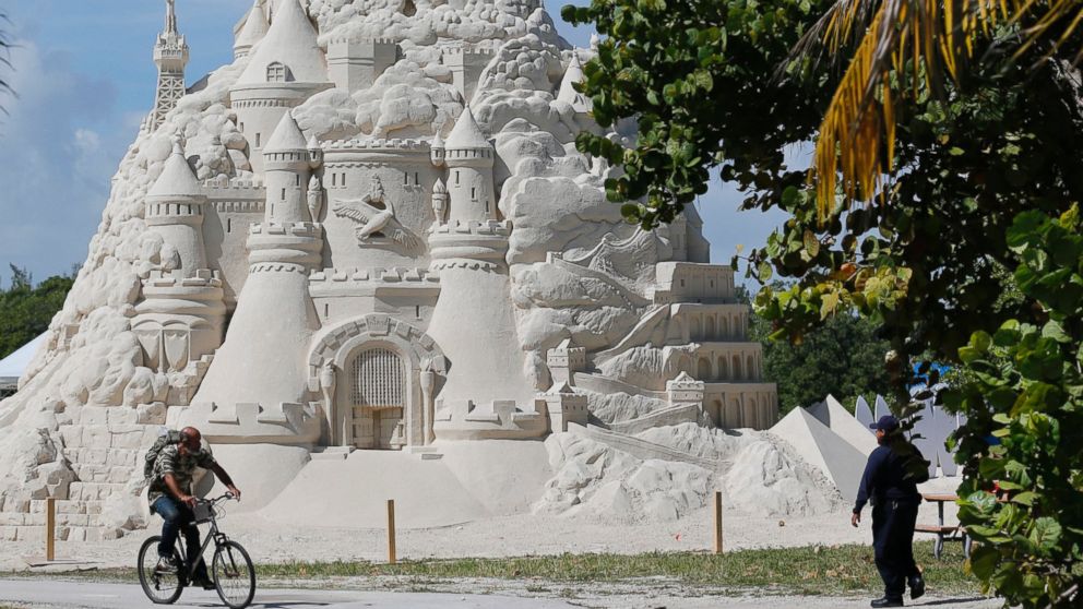 A cyclist rides past a sand castle built for a record attempt for the tallest sand castle, Monday, Oct. 26, 2015, on Virginia Key Beach in Miami.