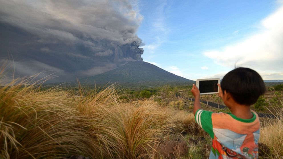 A boy takes pictures during Mount Agung's eruption seen from Kubu sub-district in Karangasem Regency on Indonesia's resort island of Bali, Nov. 26, 2017. 

