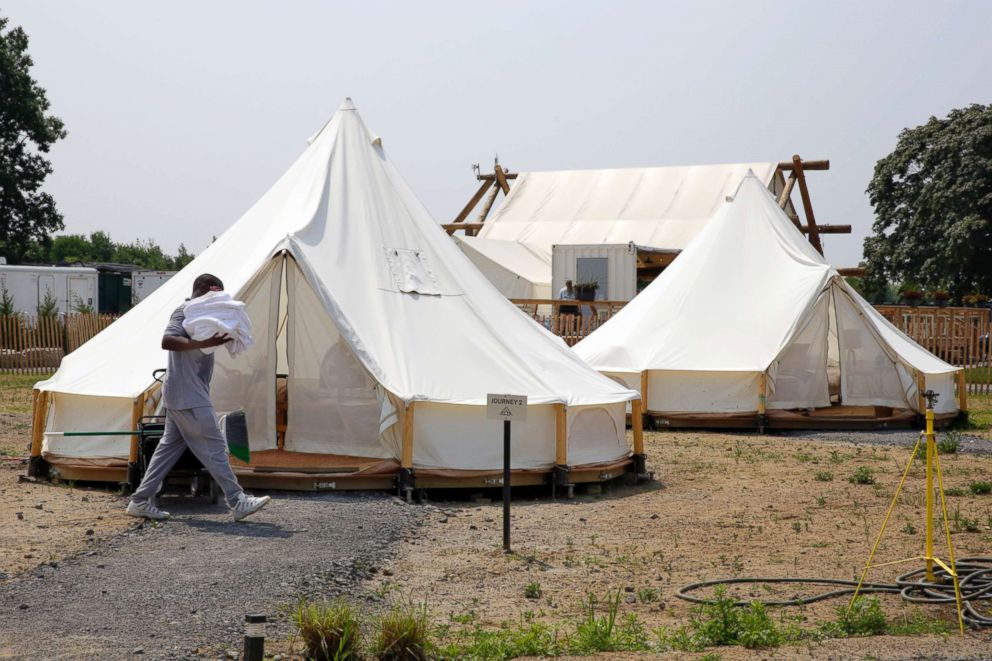 PHOTO: Housekeeping worker Deijon Wright carries towels as he makes up some of Collective Retreats' Journey Tents on Governor's Island in New York, July 3, 2018.