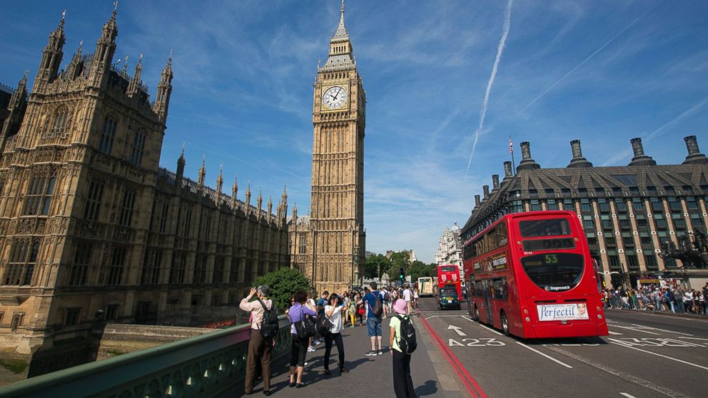 Tourists stand on Westminster Bridge as they take photographs of the Big Ben clock tower at the Houses of Parliament from Westminster Bridge in London, U.K., on July 15, 2013. 