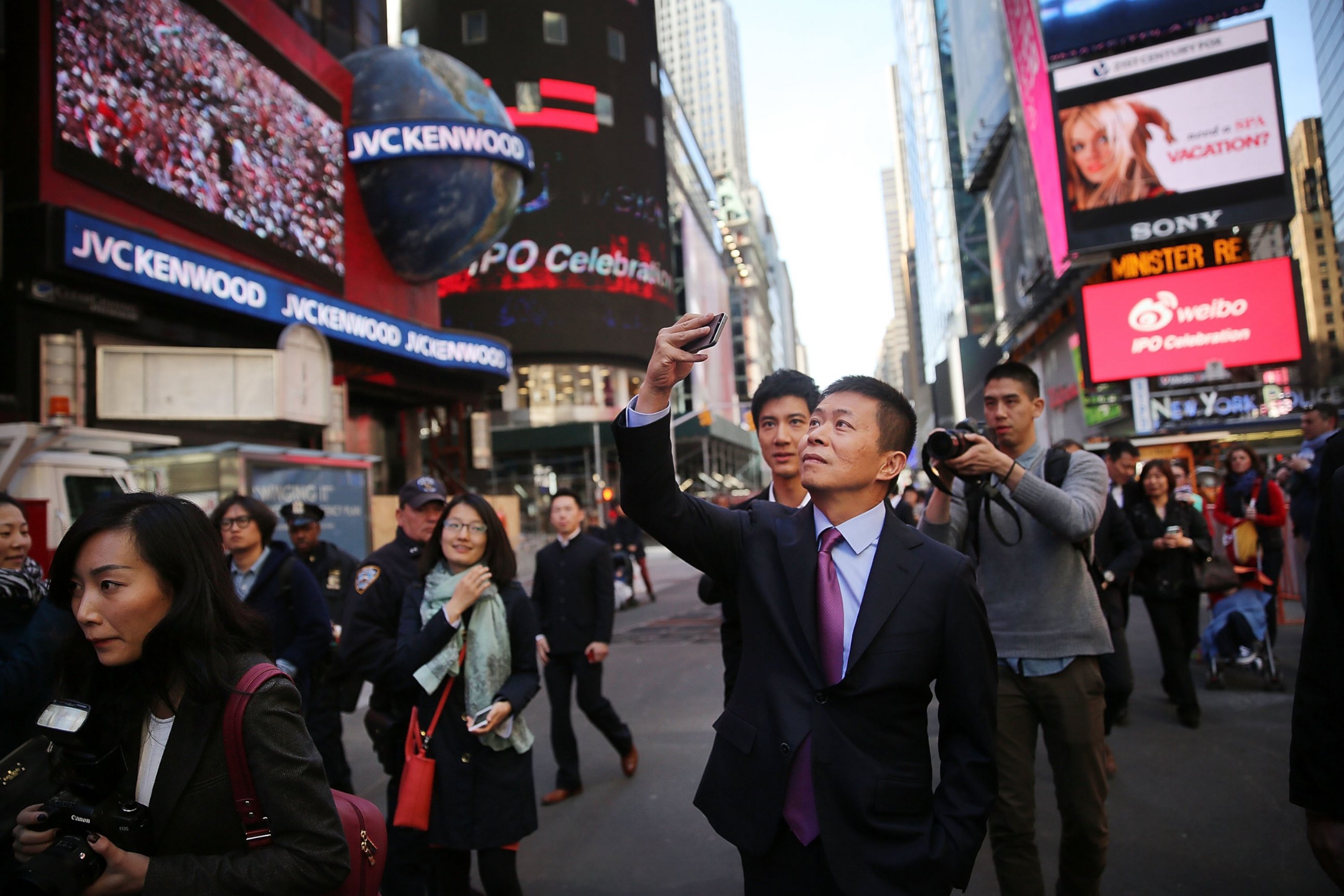 PHOTO: China's Weibo CEO Charles Chao takes a cell phone picture in Times Square moments after Weibo began trading on the Nasdaq exchange, April 17, 2014 in New York City.