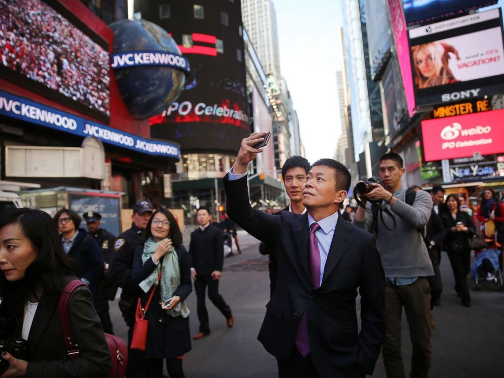 PHOTO: Chinas Weibo CEO Charles Chao takes a cell phone picture in Times Square moments after Weibo began trading on the Nasdaq exchange, April 17, 2014 in New York City.