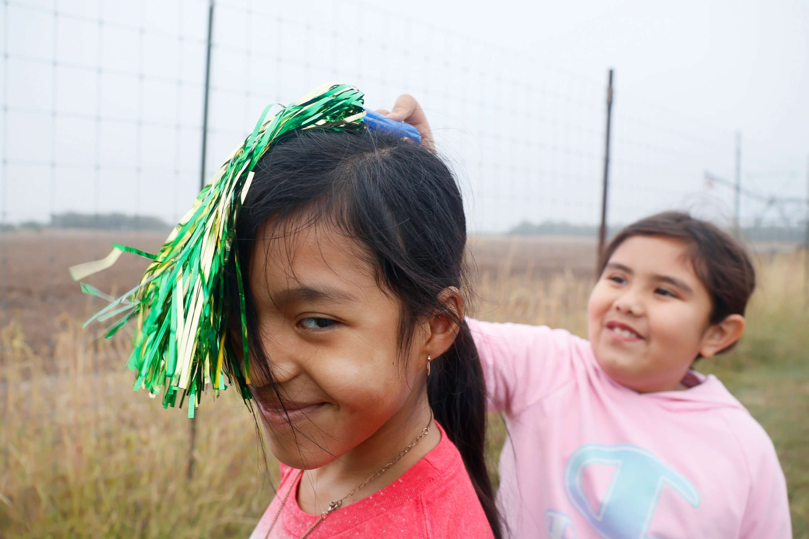 PHOTO: Athena's two friends, Joy and Velen, play with a pompom at her brother's football game in Uvalde, Texas, on Oct. 21, 2022.