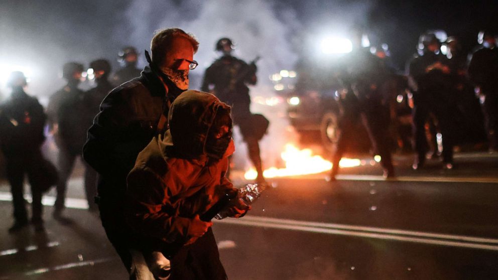 PHOTO: A protester is helped by another to retreat after clashing with the police on the 100th consecutive night of protests against police violence and racial inequality, in Portland, Oregon, on September 5, 2020.