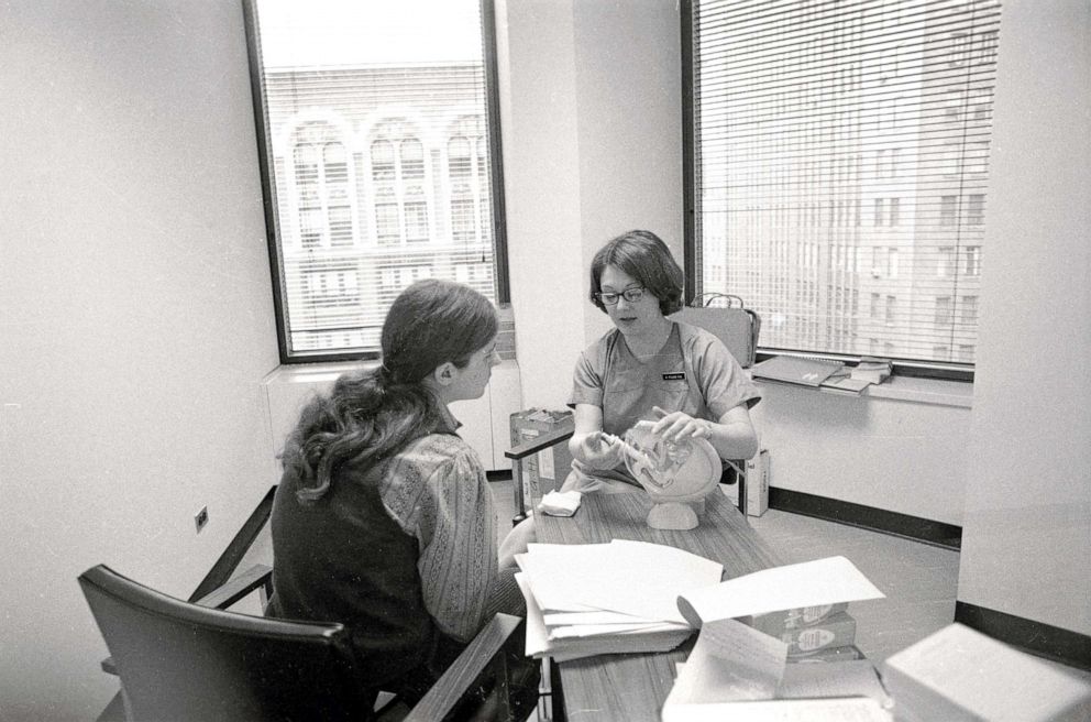 PHOTO: A clinic member shows a patient a model of the female reproductive system in the waiting room of the Women's Medical Services abortion clinic in New York, on July 7, 1971.