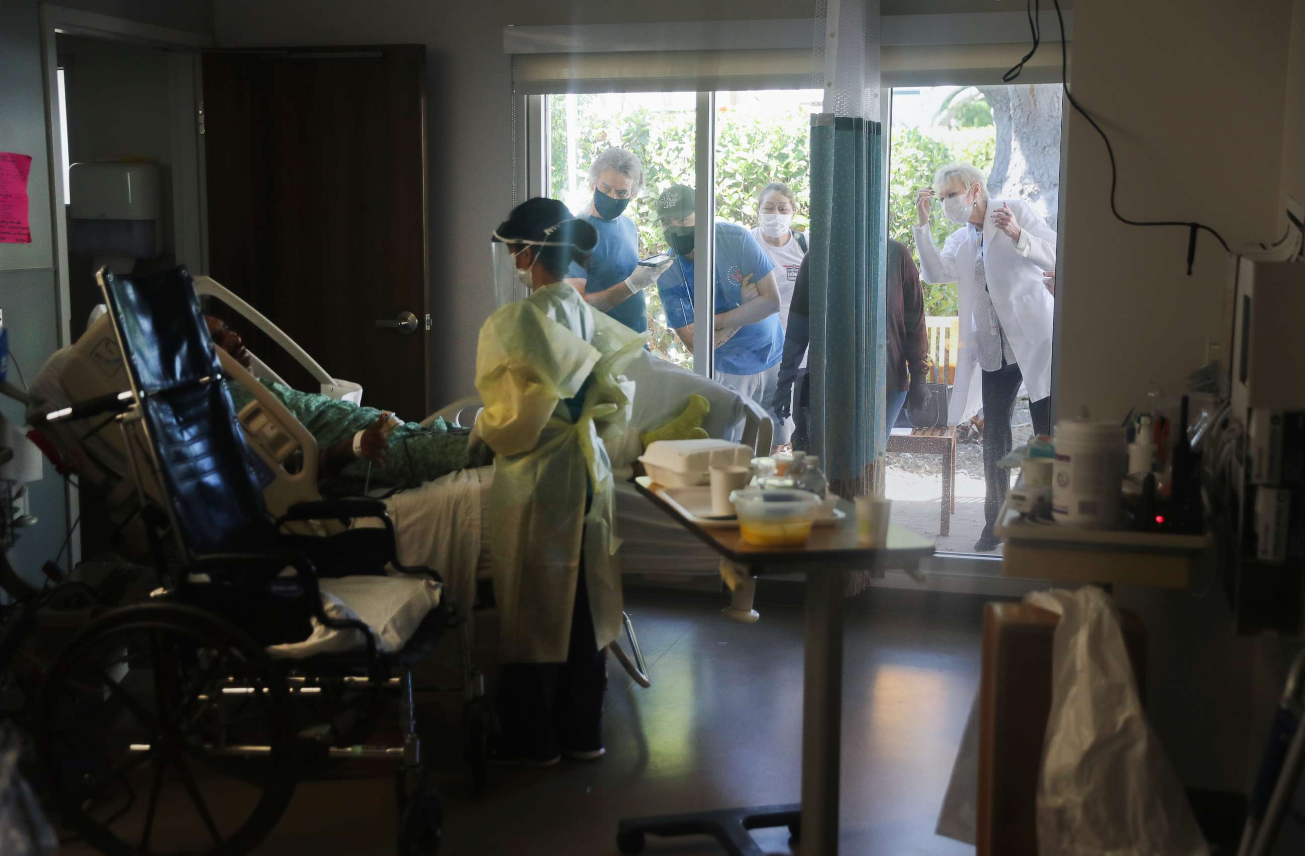 PHOTO: CORONADO, CALIFORNIA - MAY 07:  Family members and a caregiver watch from outside COVID-19 patient Isaias Perez Yanez's room, as he is assessed by occupational therapist Jaclyn Lien in the Progressive Care Unit (PCU) at Sharp Coronado Hospital.