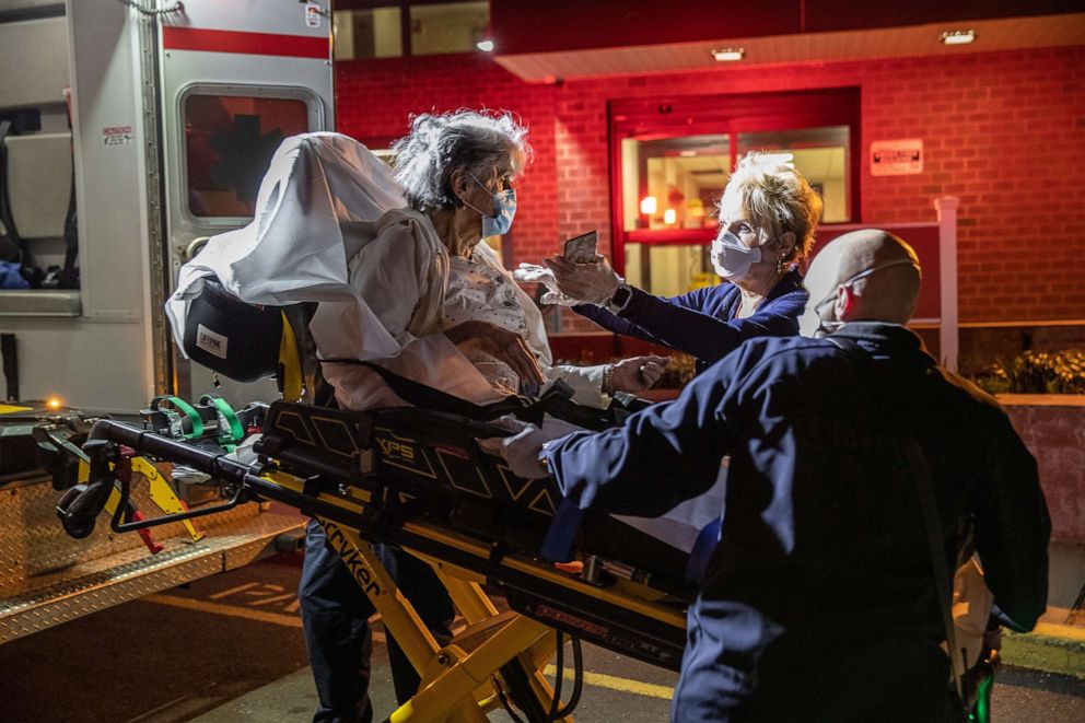 PHOTO: Linda Jaworski, with gloved hands, reaches out to touch her mother Janet Gazo, 89, who was transported to Stamford Hospital with COVID-19 symptoms, on April 3, 2020, in Stamford, Conn.