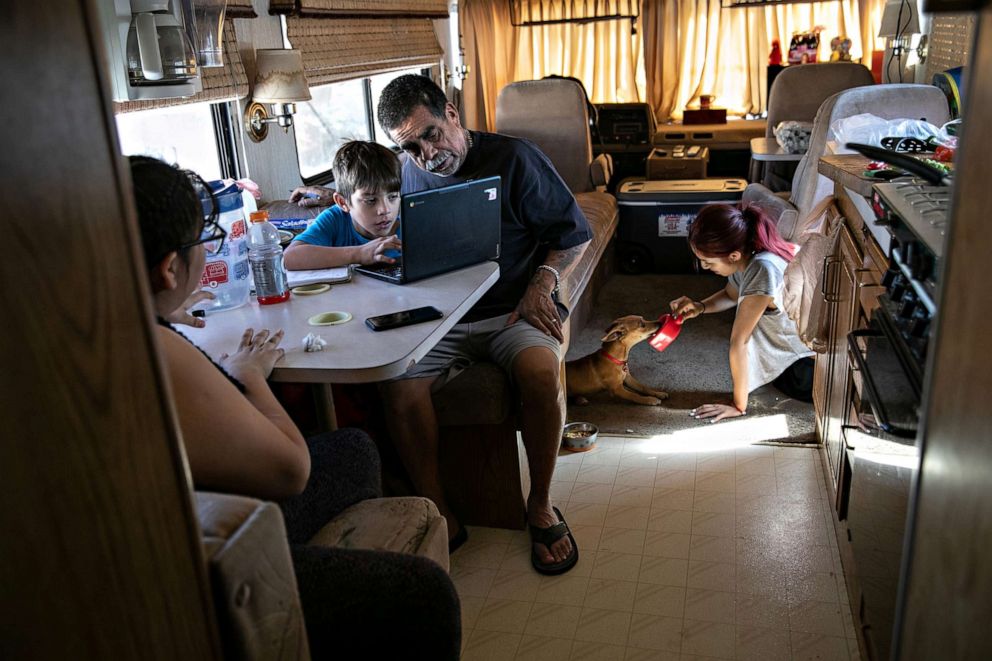 PHOTO: In this Oct. 9, 2020, file photo, Hector Medrano helps his son Angel, 8, with distance learning while in their RV in Phoenix.
