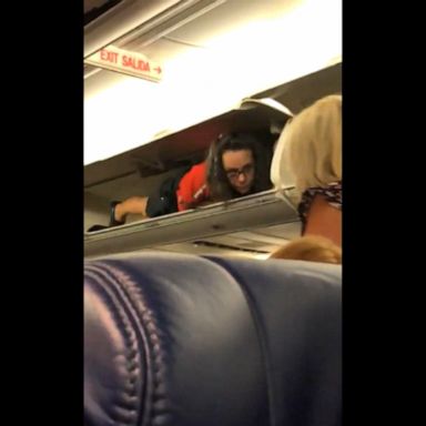 PHOTO: A Southwest flight attendant was filmed attempting to make the boarding process a little less mundane by climbing into the overhead bin and talking to passengers as they passed through the aisle.