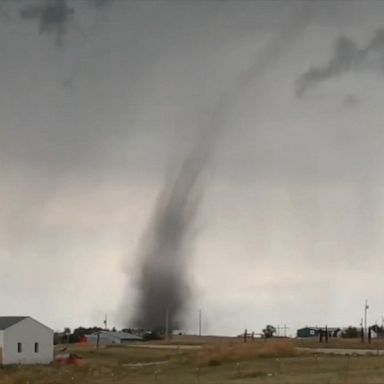 A landspout tornado crossed an interstate in Wyoming, threatening buildings before eventually dispersing. 