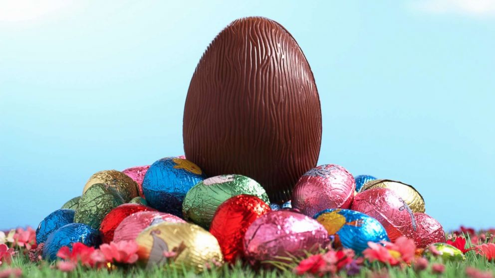 PHOTO: A chocolate egg sits on pile of foil wrapped Easter eggs on grass.